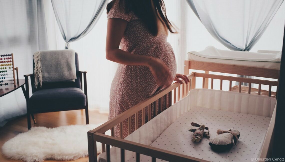 femme enceinte devant un lit bébé
