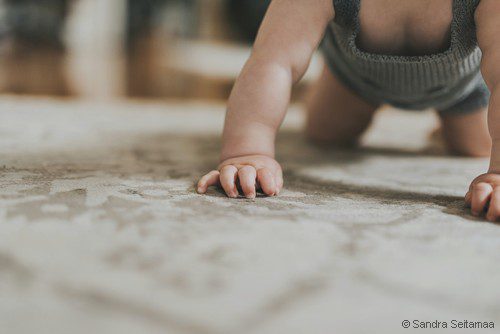 bébé fait du 4 pattes au sol sur un tapis