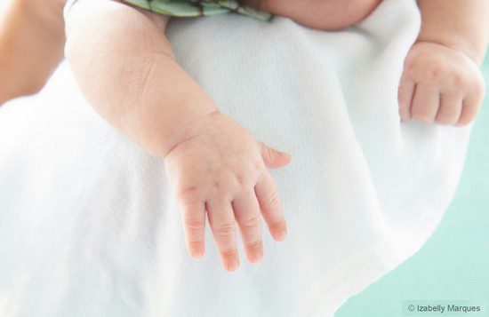 bébé porté dans les bras sur un lange