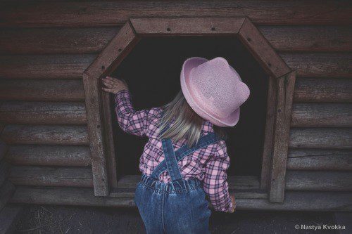 petite fille regarde à l'intérieur d'une cabane par la fenêtre