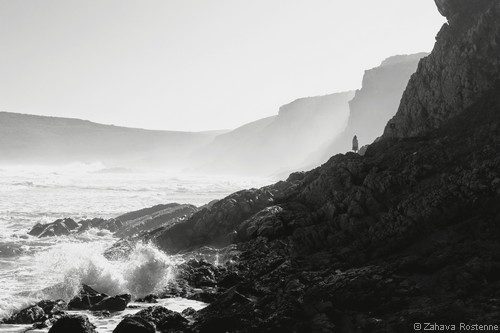 femme marche sur rochers dans la brume au bord de la mer déchaînée