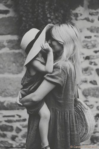maman enlace sa fille dans ses bras qui porte un chapeau