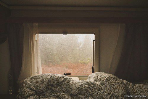 couette devant la fenêtre d'un camping-car sur la nature