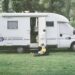assise au pied de son camping-car, une maman tient son bébé sur elle