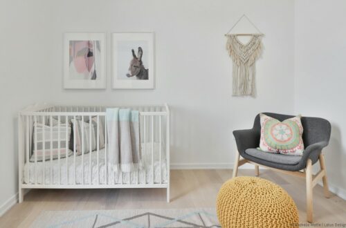 décor de chambre bébé épuré : lit à barreaux, siège, tableaux