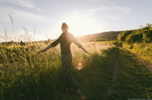 femme seule dans champ, bras écartés, soleil couchant