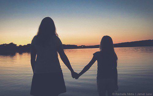 maman et fille se tiennent par la main dans le crépuscule
