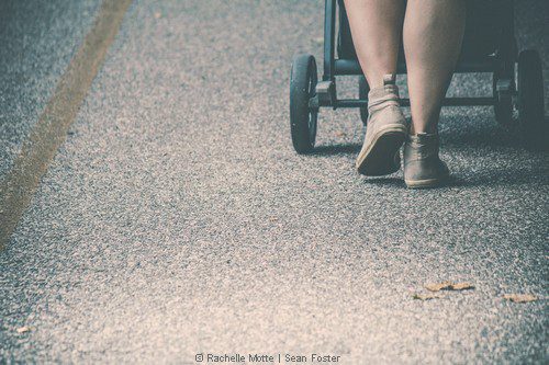 des pieds derrière une poussette dans la rue
