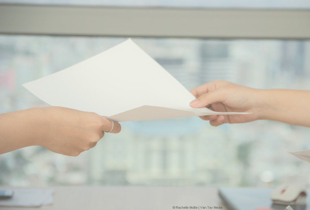 deux mains se transmettent une feuille
