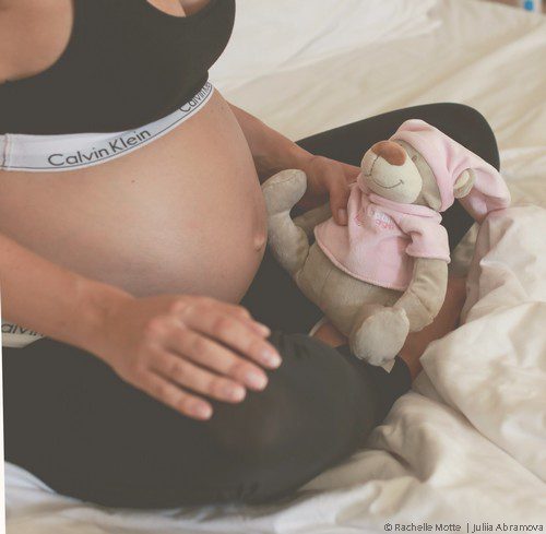 femme enceinte assise en tailleur tenant une peluche