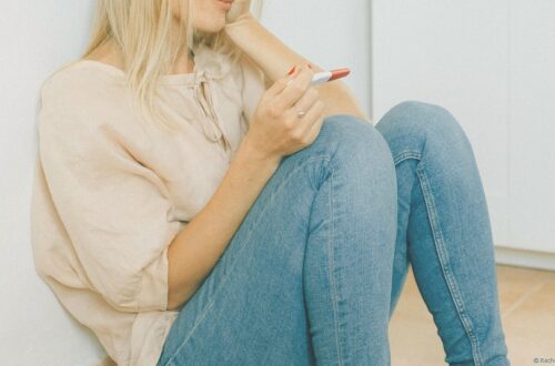 femme assise au sol, un test de grossesse dans la main